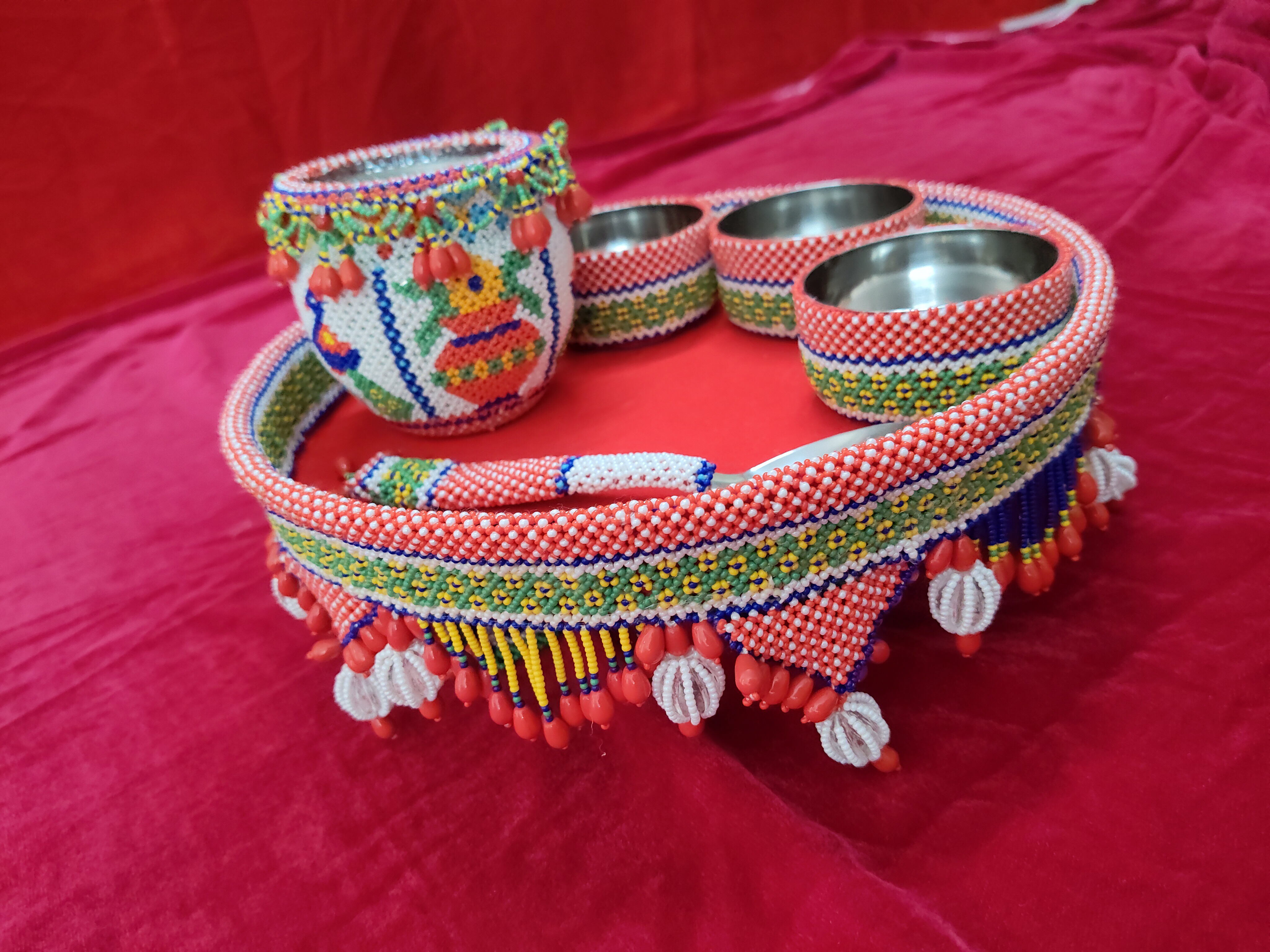 Colourful beaded matka set with intricate geometric patterns on red background